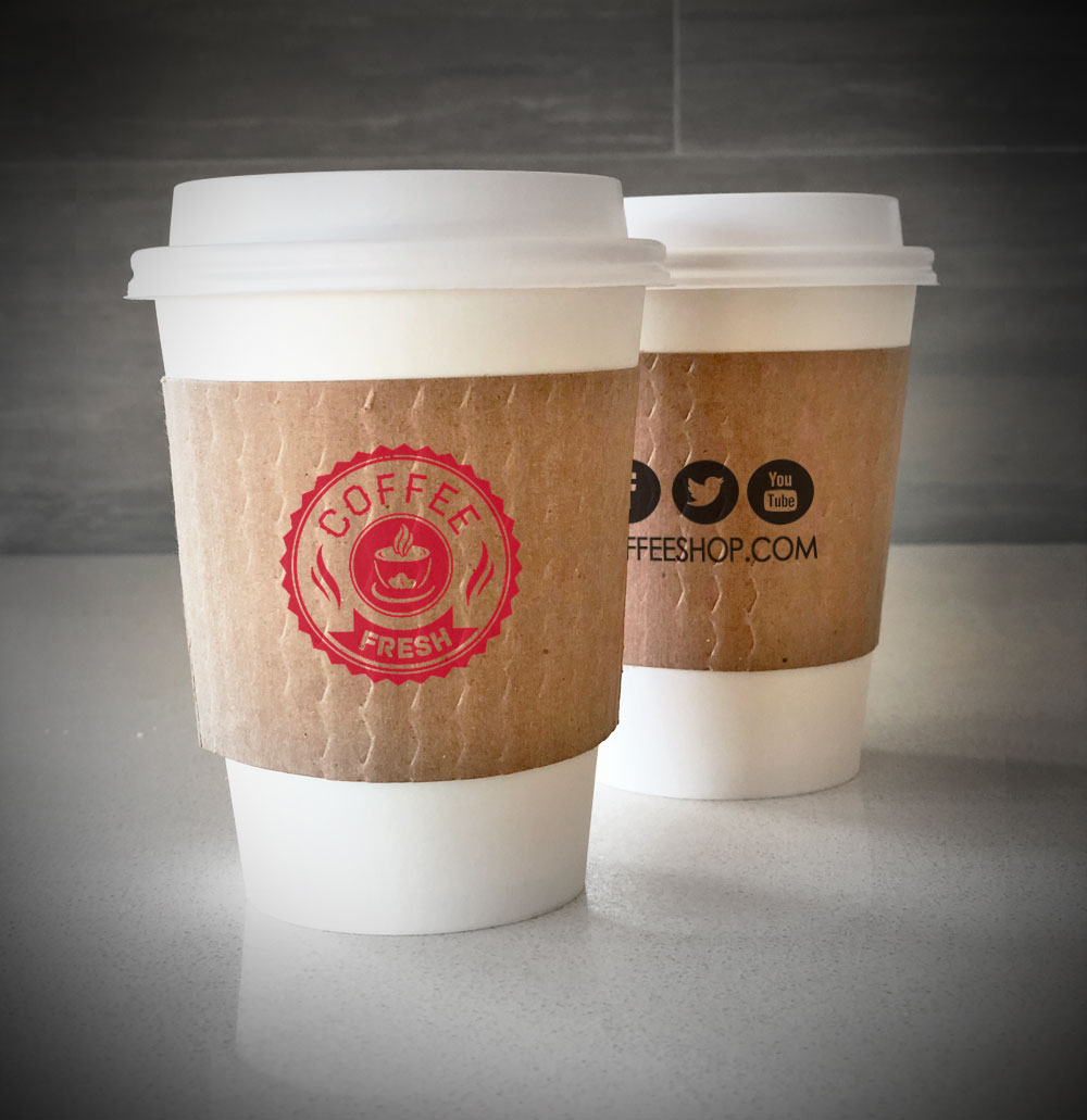 Printed coffee cup sleeve printed on kraft sleeves with one color on front and one color on back placed on 2 white paper cups and are placed on a countertop