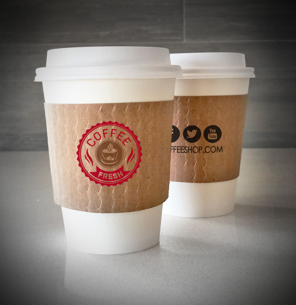 Printed coffee cup sleeves printed on kraft sleeves with two colors on front and one color on back placed on 2 white paper cups placed on countertop