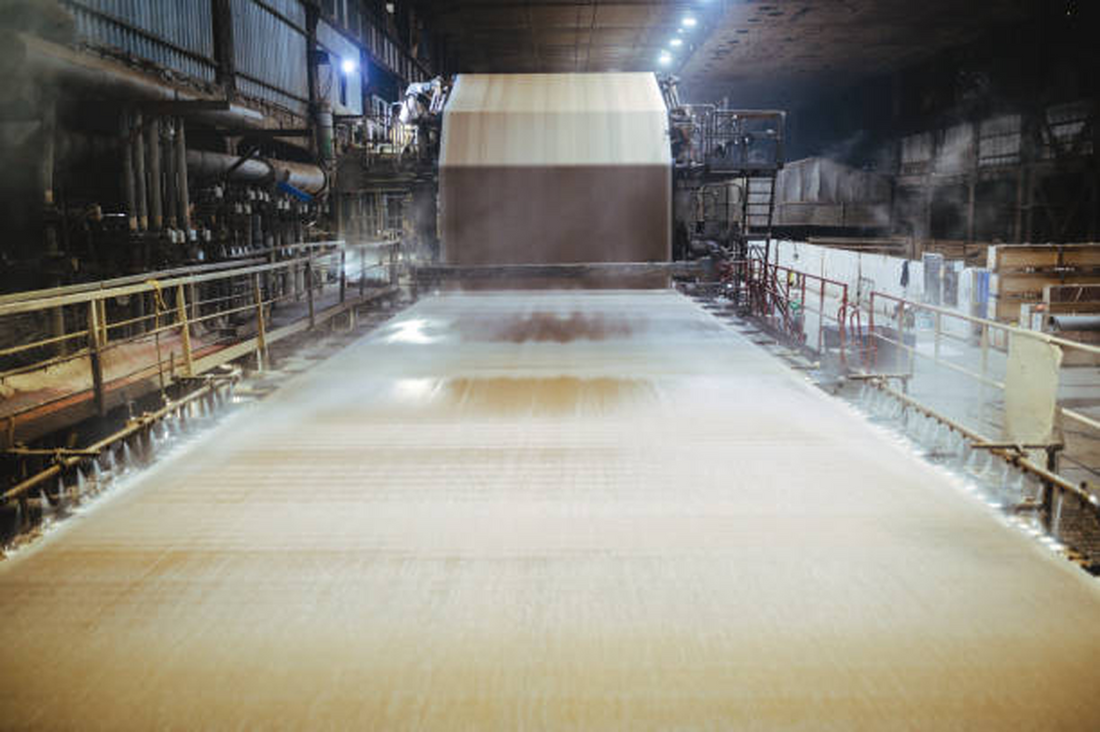 Paper mill machinery converting raw recycled paperboard rolls into materials for eco friendly coffee shop supplies