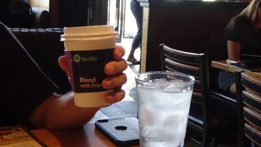 person holding custom cup sleeves in a coffee shop displaying the power branding