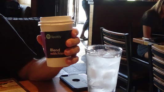 person holding custom cup sleeves in a coffee shop displaying the power branding