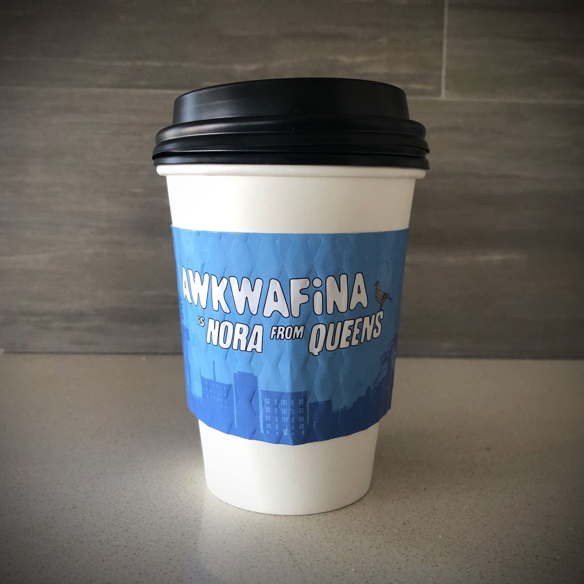 Custom printed cup sleeve printed in full placed on a white aper cup placed on a countertop