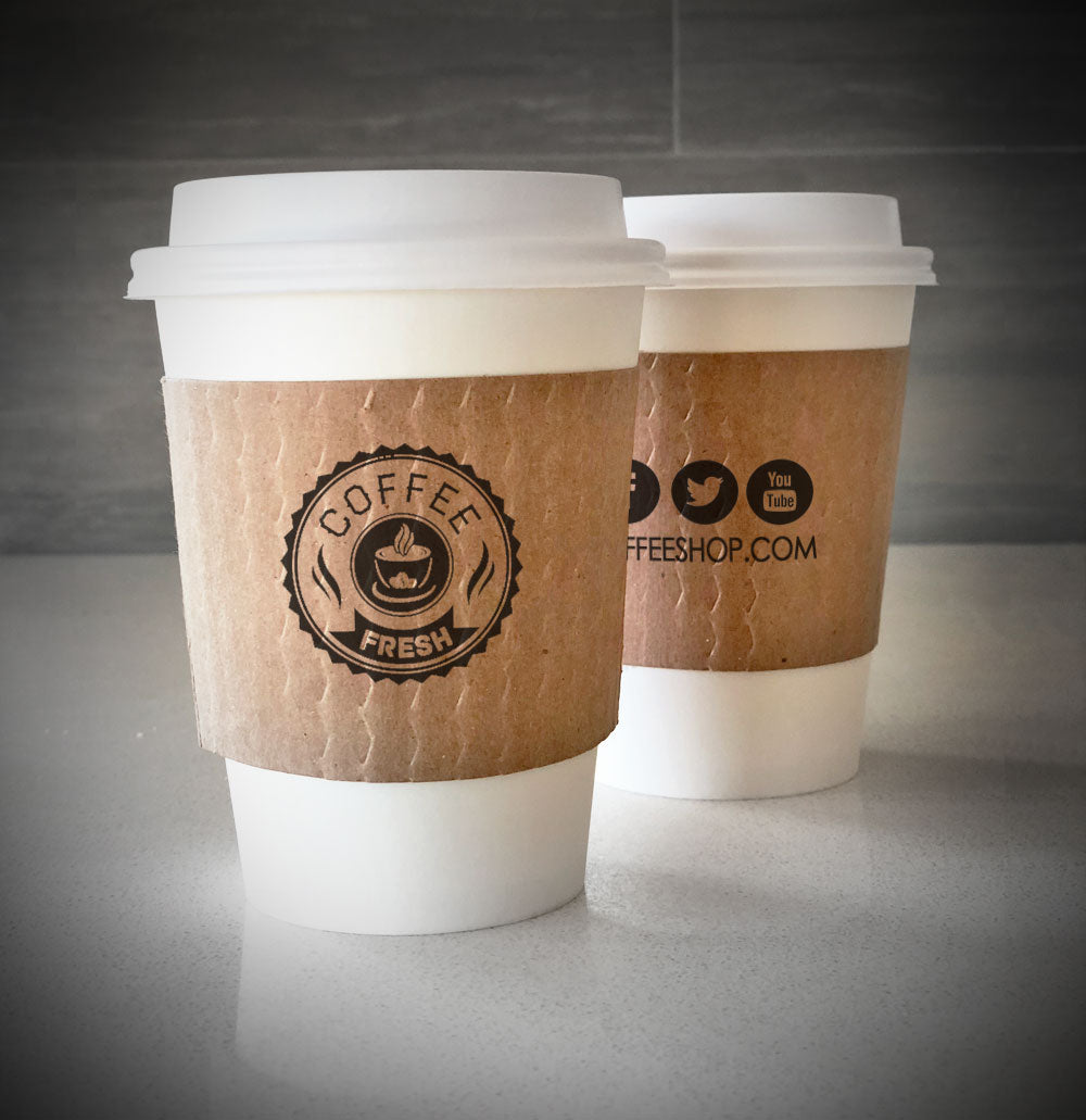 Printed coffee cup sleeves printed on kraft sleeves with one color on front and one color on back placed on 2 white paper cups sitting on countertop