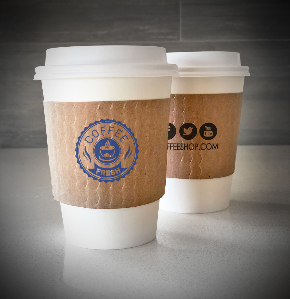 Printed coffee cup sleeves printed on kraft sleeves with one color on front and back placed on 2 white paper cups as they sit on a countertop