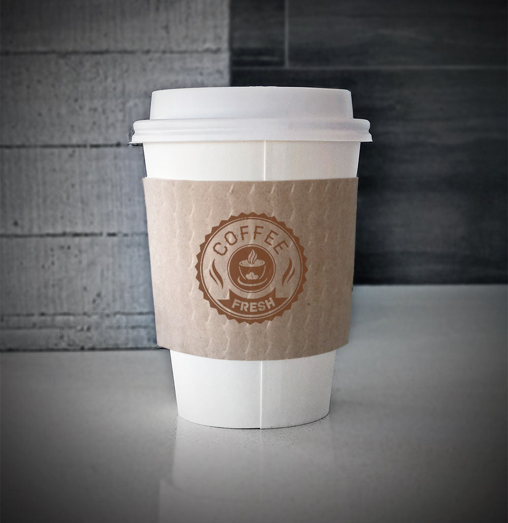 printed coffee cup sleeves printed with one color on front using kraft cup sleeves is placed on a white paper cup sitting on a countertop