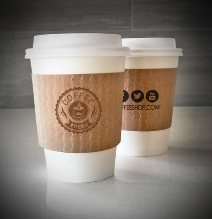 Printed coffee cup sleeves printed on kraft sleeves with one color on front and back placed on 2 white paper cups on countertop