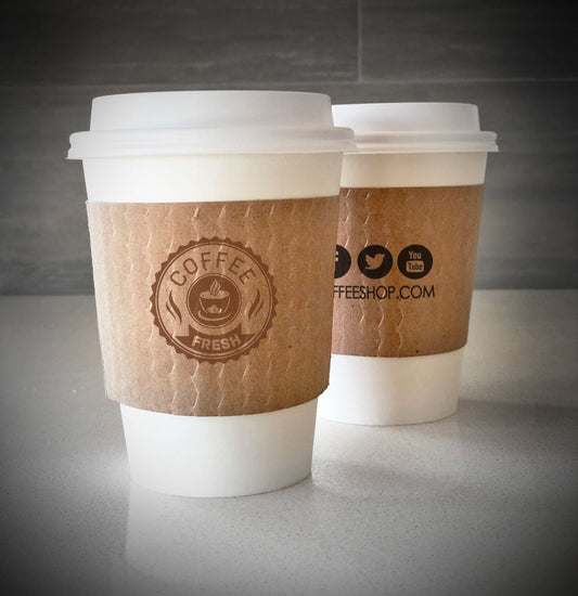 Printed coffee cup sleeves printed on kraft sleeves with one color on front and back placed on 2 white paper cups on countertop