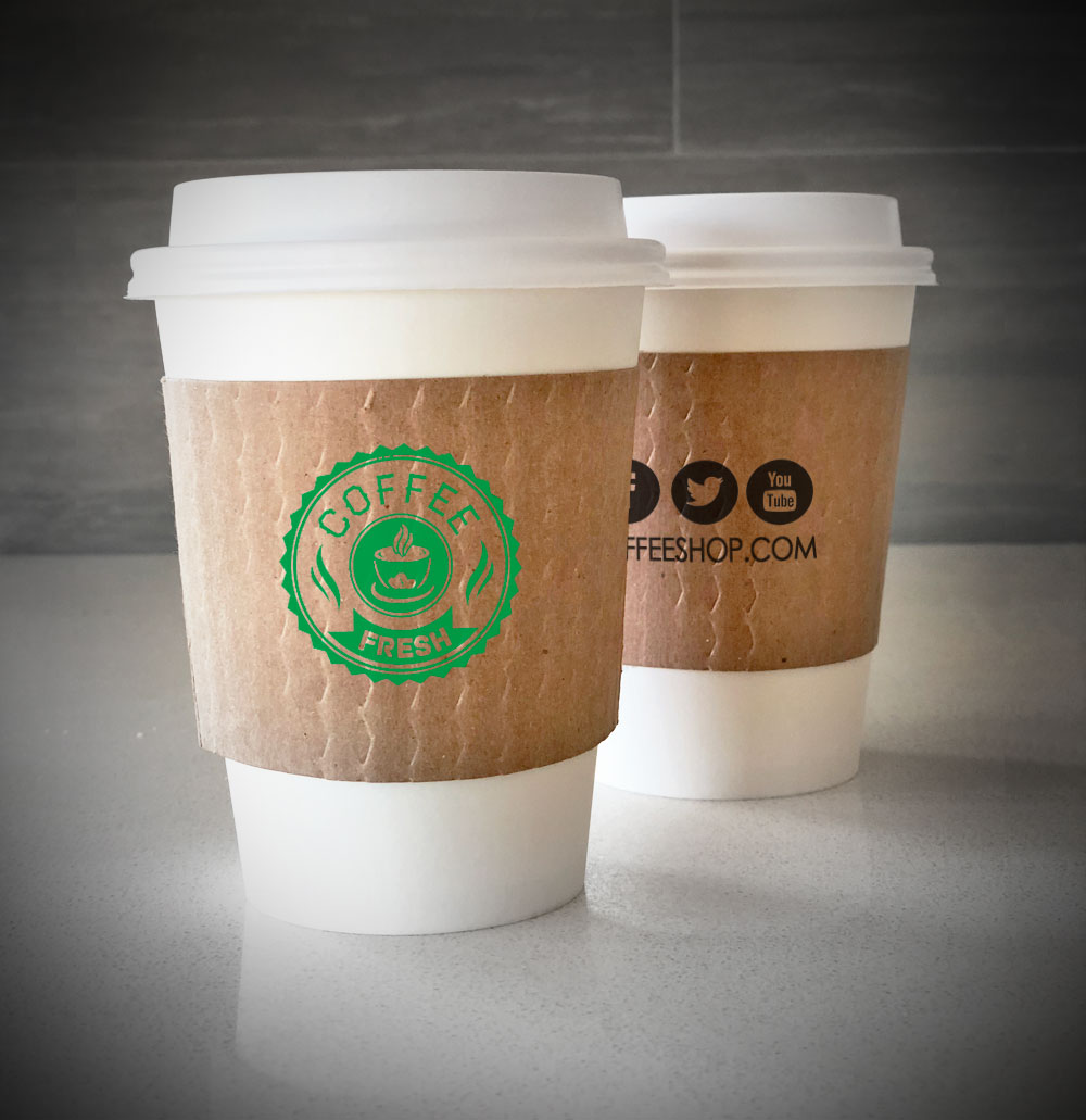 Printed coffee cup sleeves printed on kraft sleeves with one color printed on front back placed on 2 white paper cups and are placed on a countertop