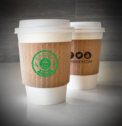Printed coffee cup sleeves printed on kraft sleeves with one color printed on front back placed on 2 white paper cups and are placed on a countertop