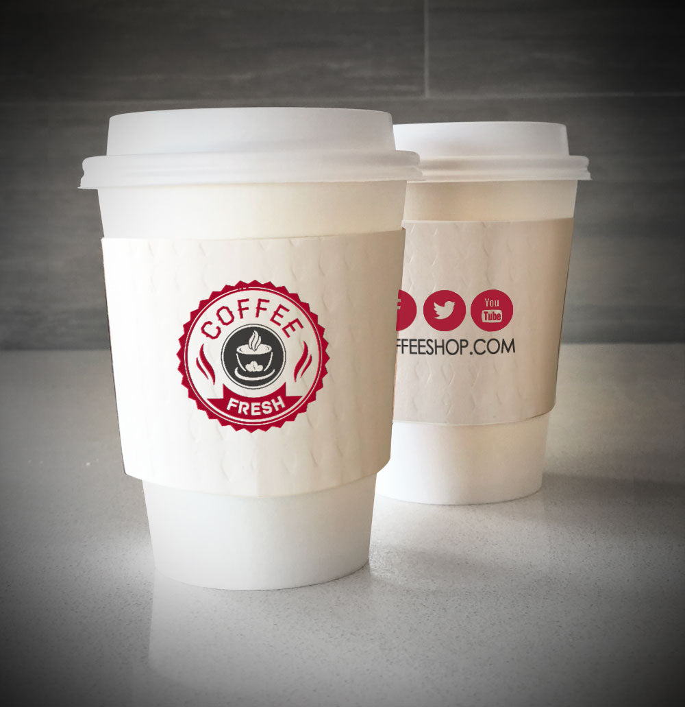 White custom printed cup sleeves printed with 2 colors on both sides placed on 2 white paper cups and are placed on countertop