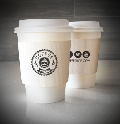 Printed coffee cup sleeves printed on white sleeves with one color on front and one color on back placed on 2 white paper cups and sitting on countertop