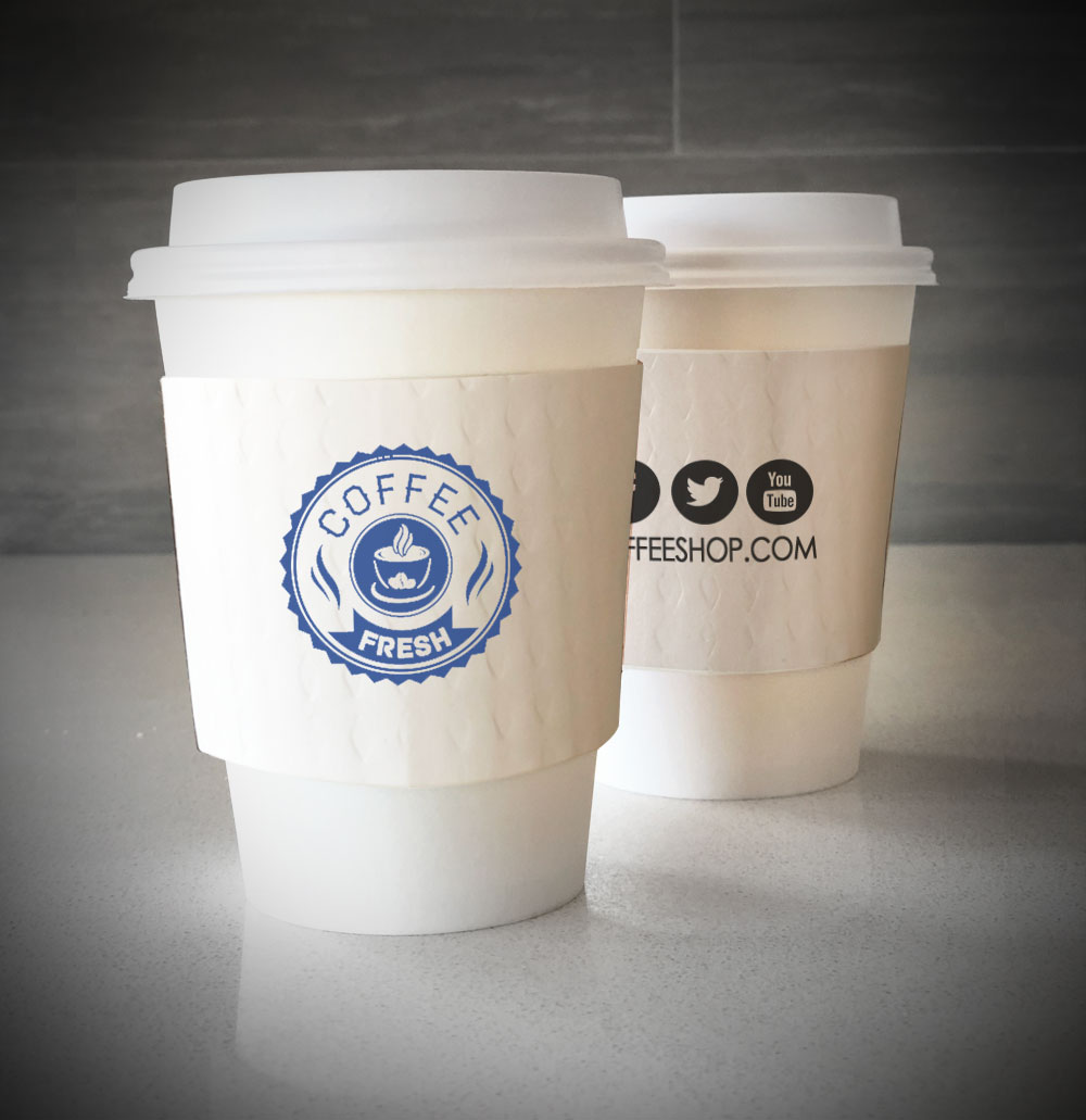 Printed coffee cup sleeves printed on white sleeves with one color on front and back placed on 2 white paper cups as they sit on a countertop