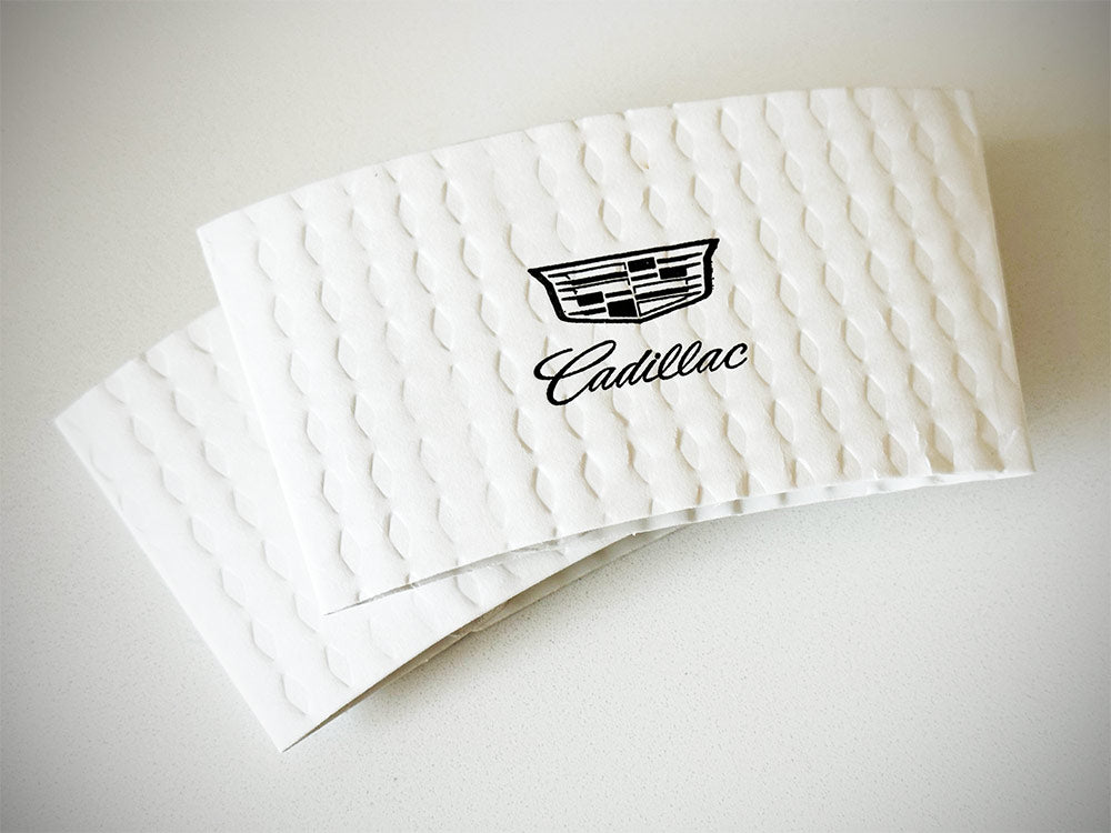 Printed coffee cup sleeves printed on white sleeves for Cadillac with one color on front placed on a tabletop