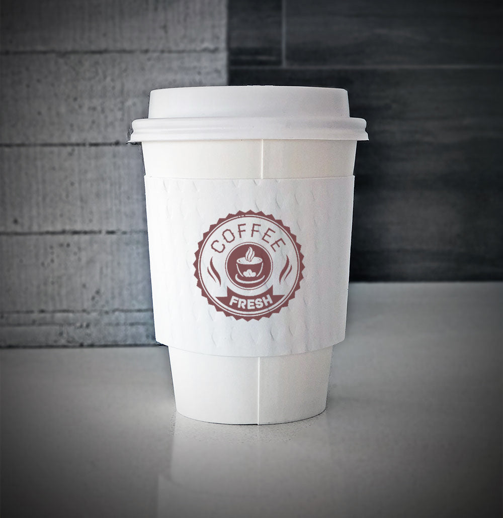 White printed coffee cup sleeves printed on front with one color wrapped around a white paper cup sitting on a countertop