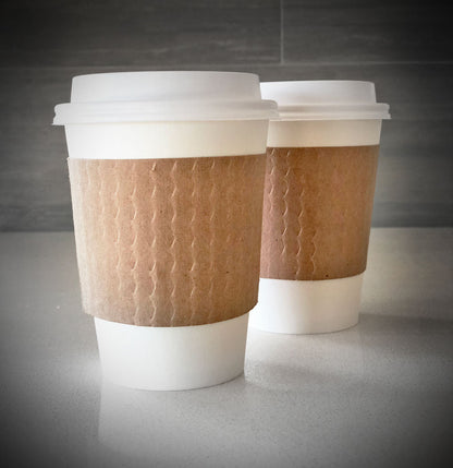kraft blank coffee cup sleeves placed on 2 white paper cups and are placed on a countertop